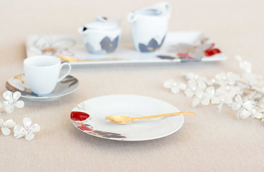 White saucer with colorful design teacup and flowers on pink background