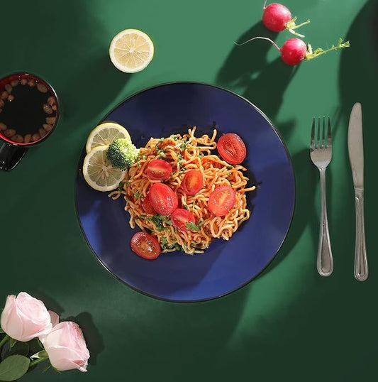 Noodles with vegetables on a blue plate with a green background