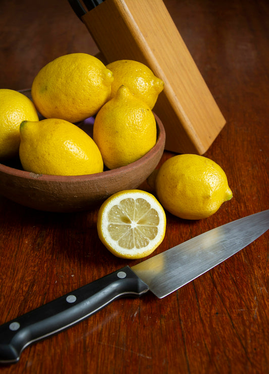 sliced lemon beside black handled knife on brown wooden table