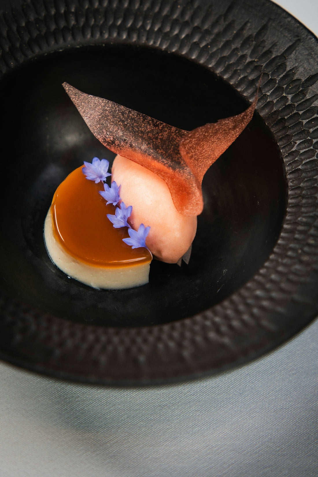 Gourmet dessert with fruit, caramel, and edible flower