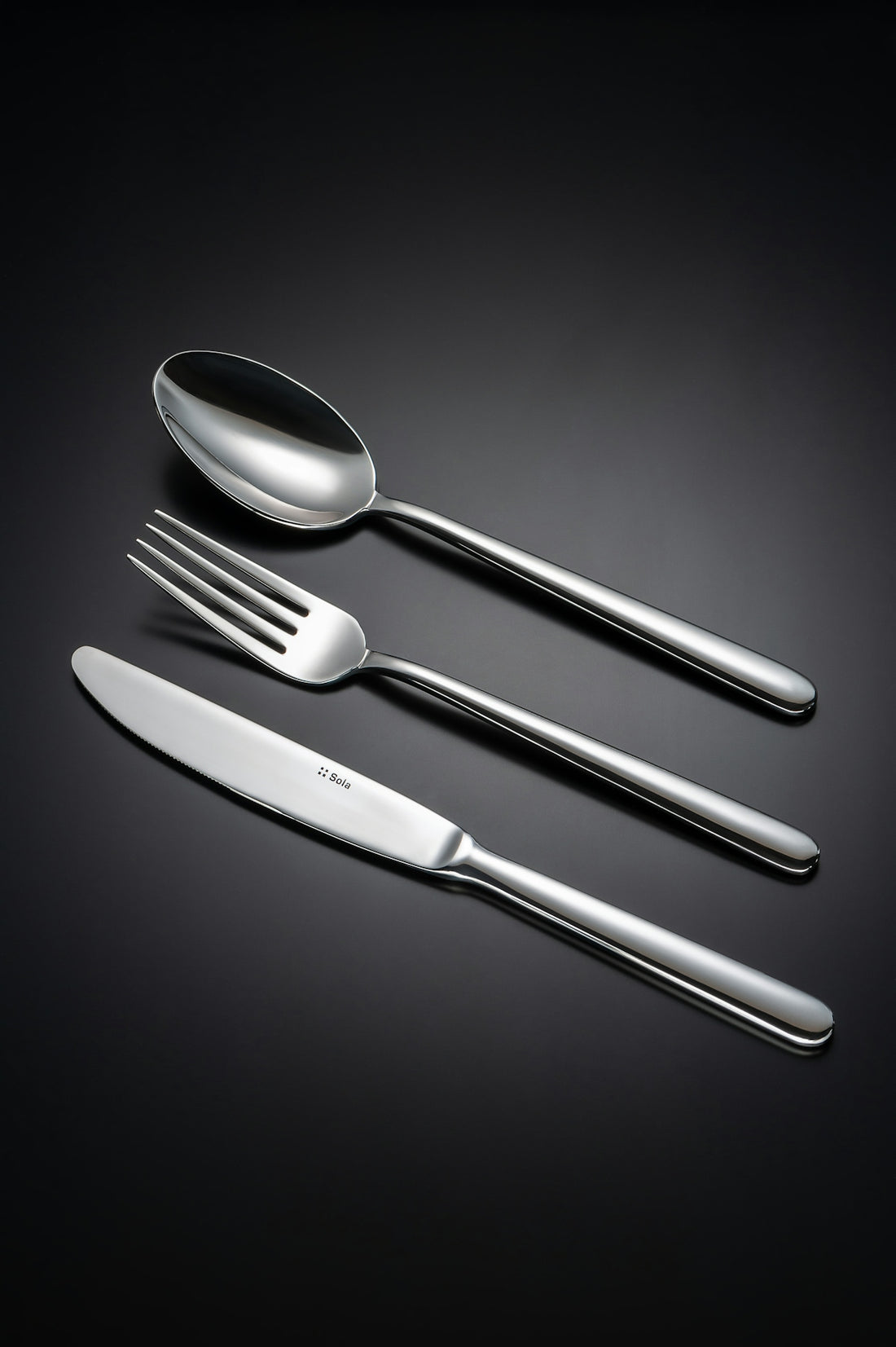 A spoon, fork, and knife on a black background.