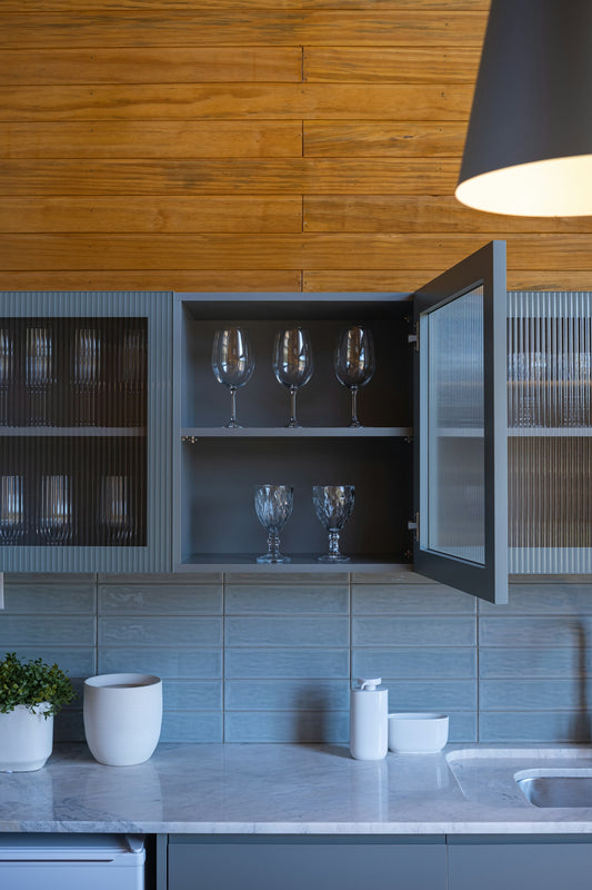 Kitchen cabinets with glassware and wooden wall paneling.