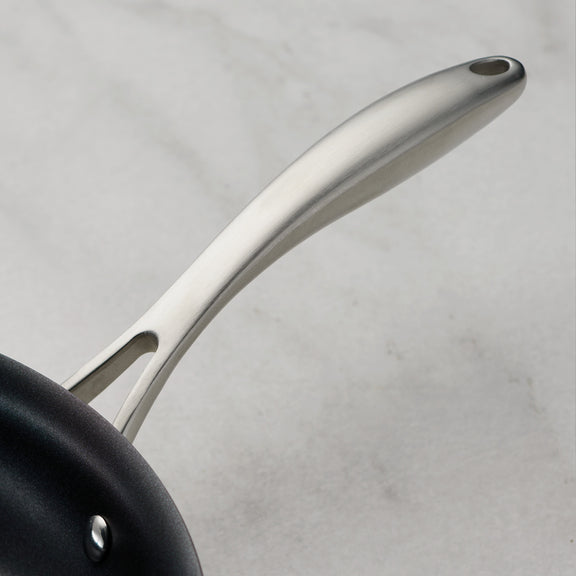 Close-up of a black frying pan with a silver handle on a light gray background