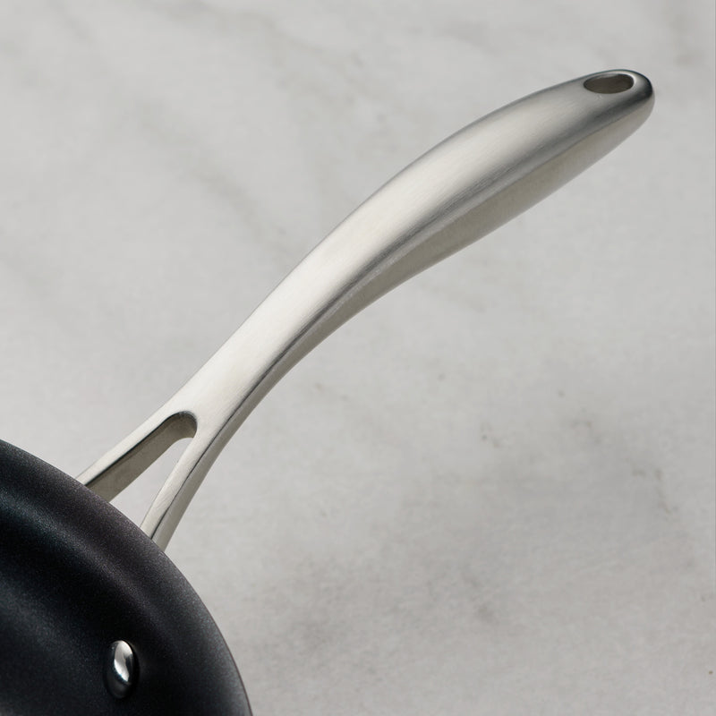 Close-up of a black frying pan with a silver handle on a light gray background