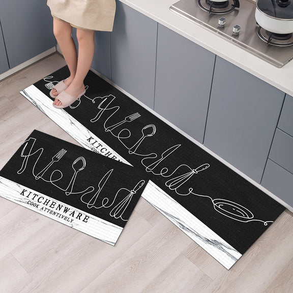 Two black kitchen mats with white text and graphics on a wooden floor.