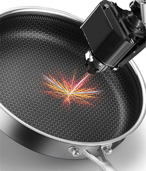 Close-up of a frying pan with a light source creating a colorful pattern on the surface.