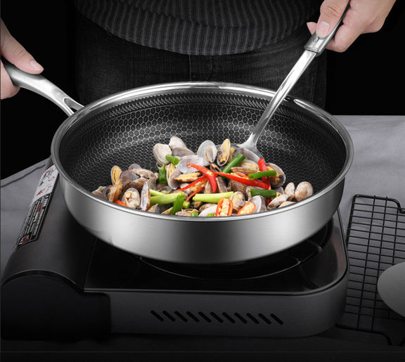 Person cooking seafood and vegetables in a non-stick frying pan on a stove.