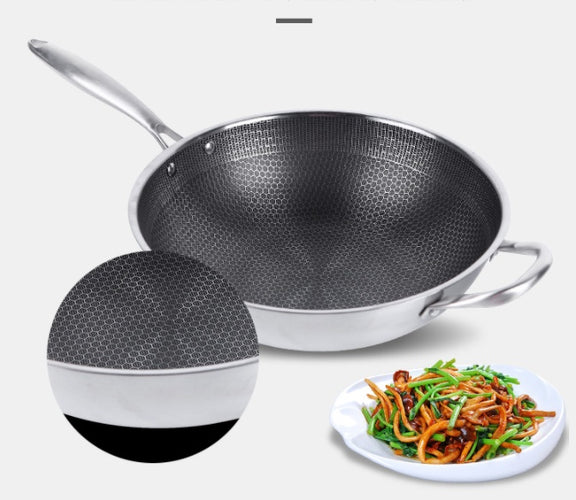 Stainless steel wok with a plate of stir-fry on a white background