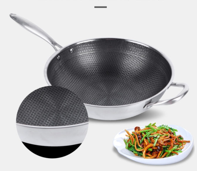 Stainless steel wok with a plate of stir-fry on a white background