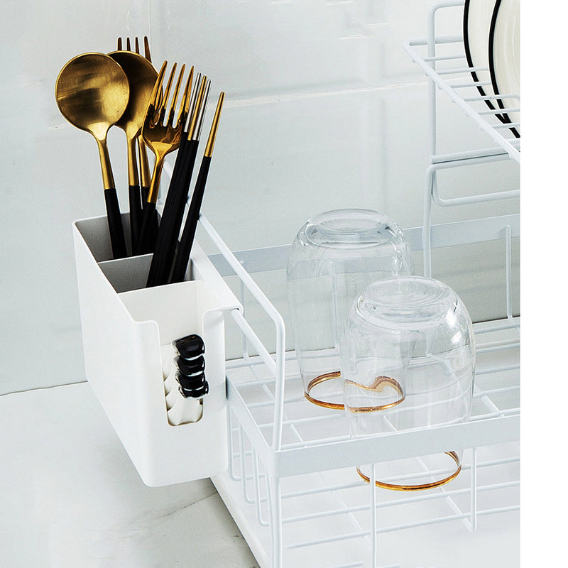 White kitchen organizer with gold and black cutlery and glasses on a white countertop.