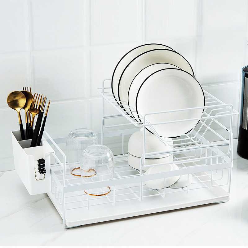 White dish rack with plates, bowls, and utensils on a white surface.