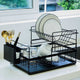 Black dish rack with white plates and gold utensils on a kitchen counter.