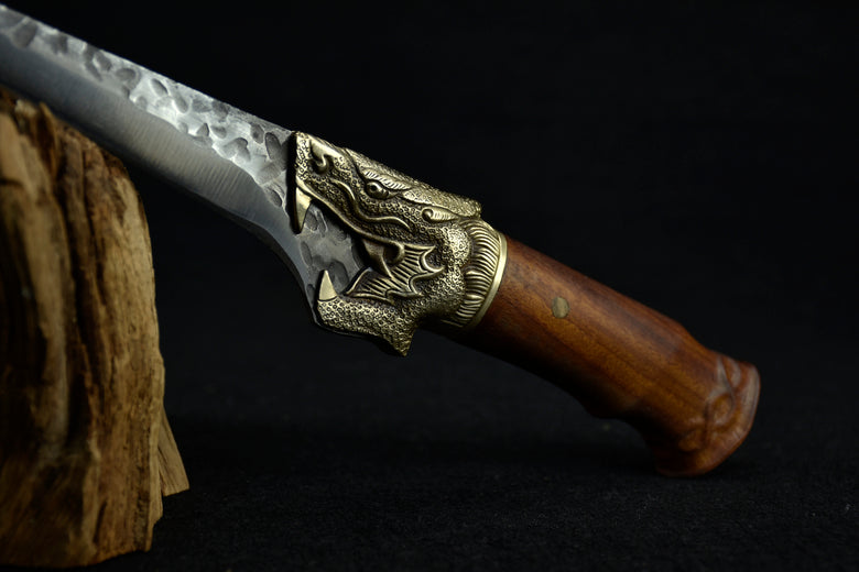 Decorative knife with wooden handle and metal blade on a dark background