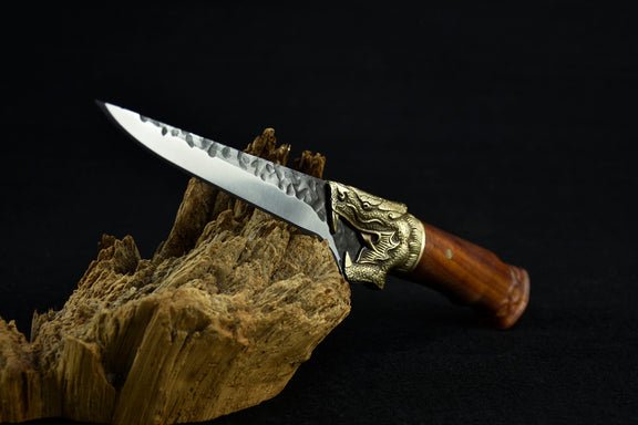Decorative knife with a wooden handle and metal blade on a dark background