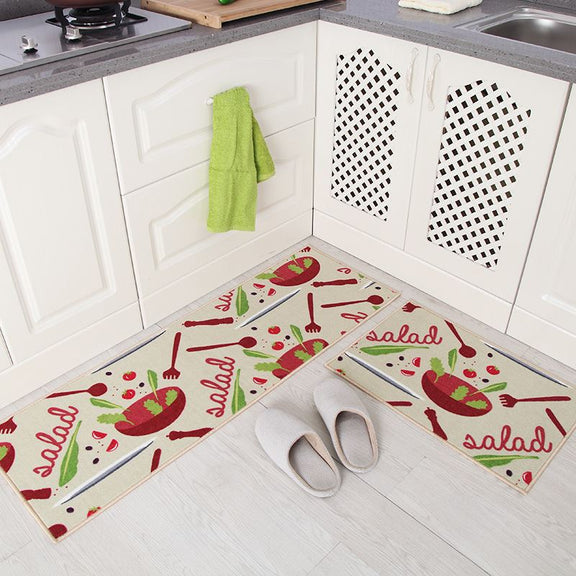 Kitchen floor with salad-themed mats and a green towel hanging on a cabinet.