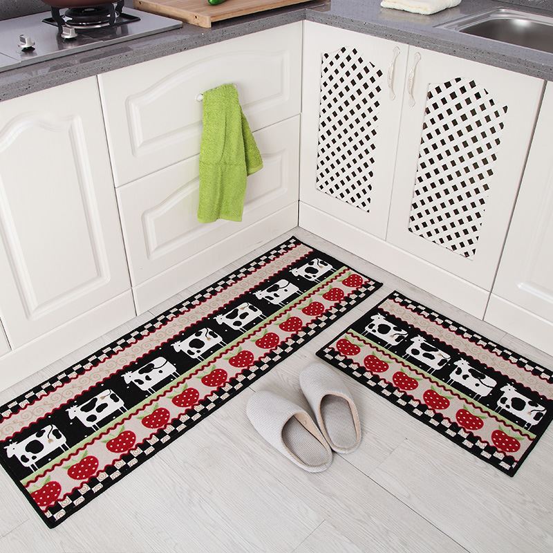 Two kitchen mats with cow and polka dot pattern on a floor in a kitchen setting.