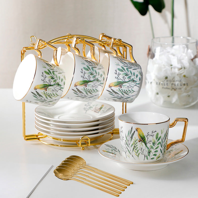Ceramic tea set with floral design on a white surface, featuring cups, saucers, and a gold stand.