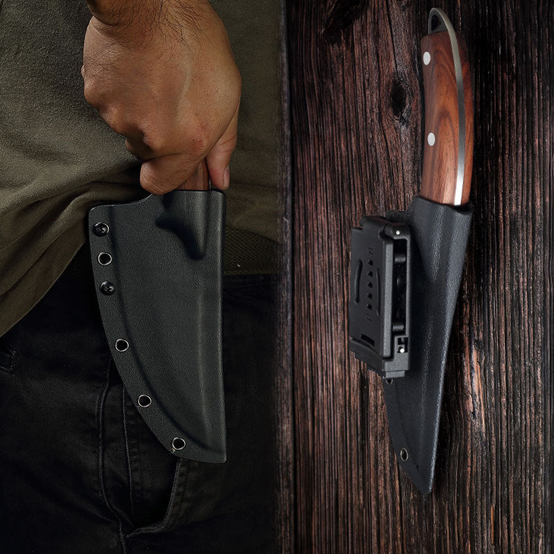 Hand holding a knife sheath next to a knife with a wooden handle on a wooden surface