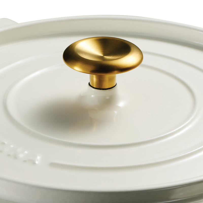 White dutch oven pot with a gold lid knob on a white background