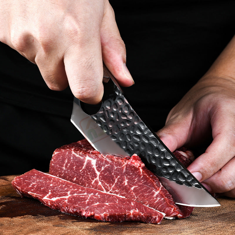 Person cutting raw meat with a knife on a wooden surface