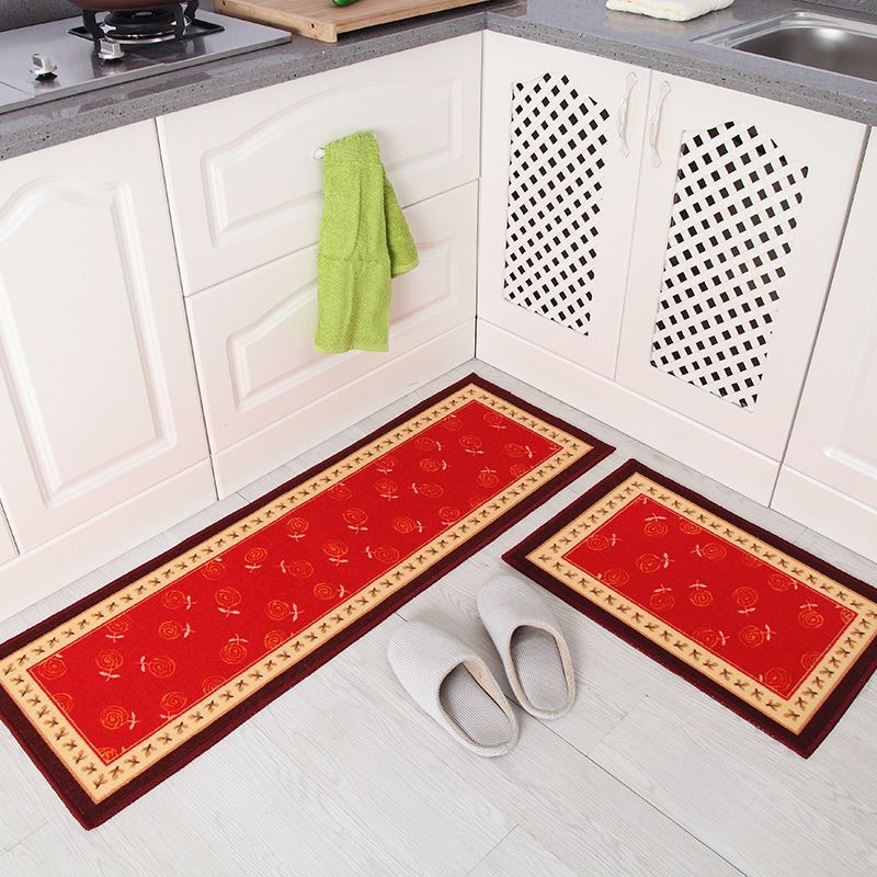 Red kitchen mats with a pattern on a white floor in a kitchen setting.
