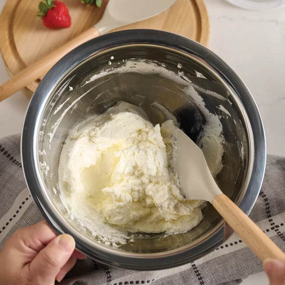 Bowl of whipped cream with a spatula on a kitchen counter