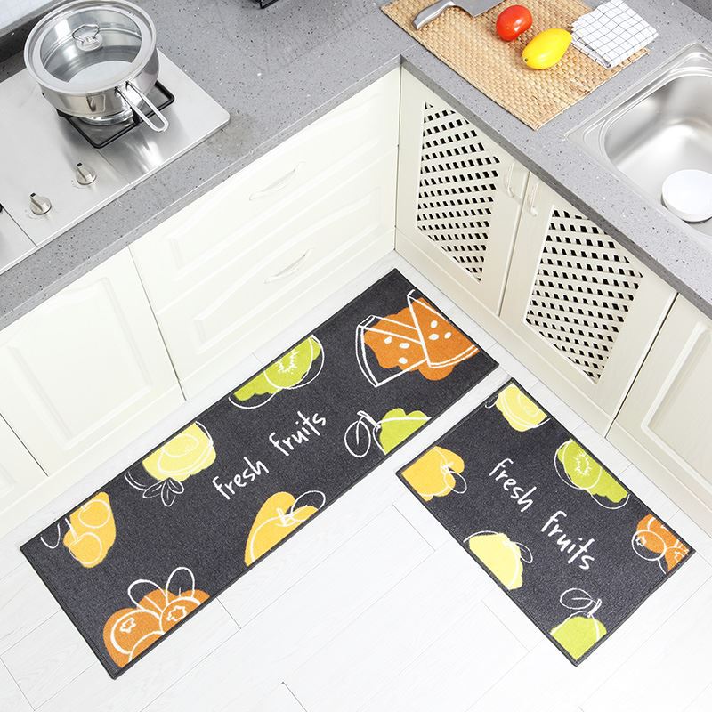 Two kitchen mats with fruit patterns on a tiled floor.
