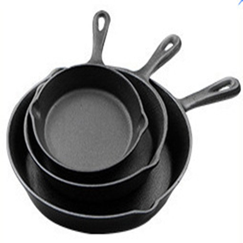 Set of three black cast iron skillets on a white background