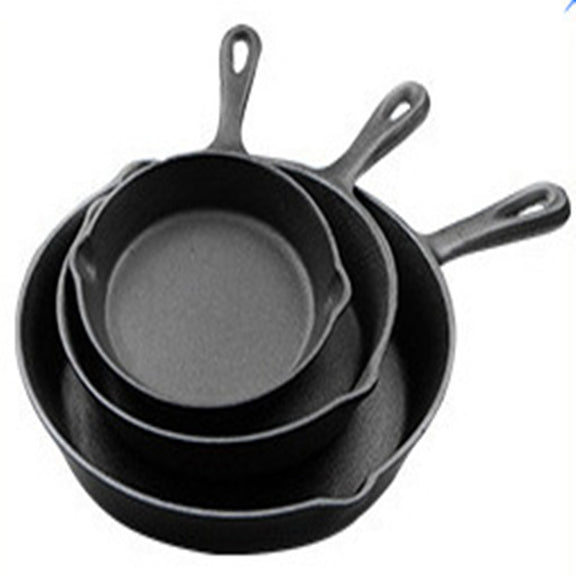 Set of three black cast iron skillets on a white background