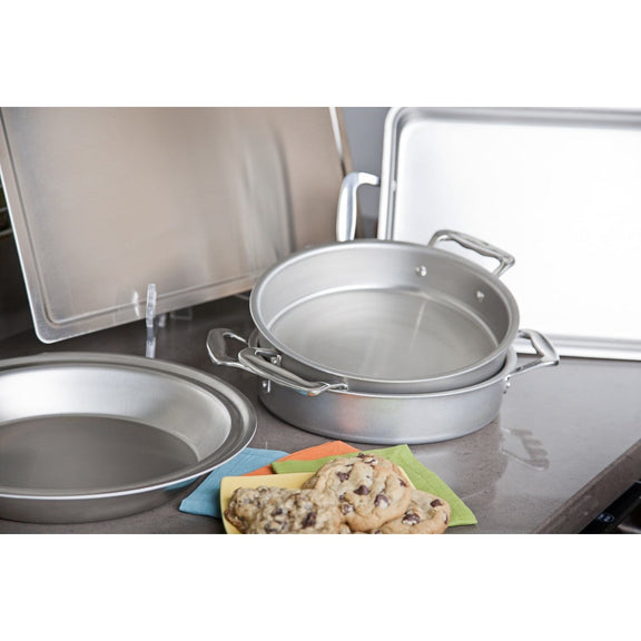 Set of metal baking pans on a kitchen counter with cookies in the foreground.