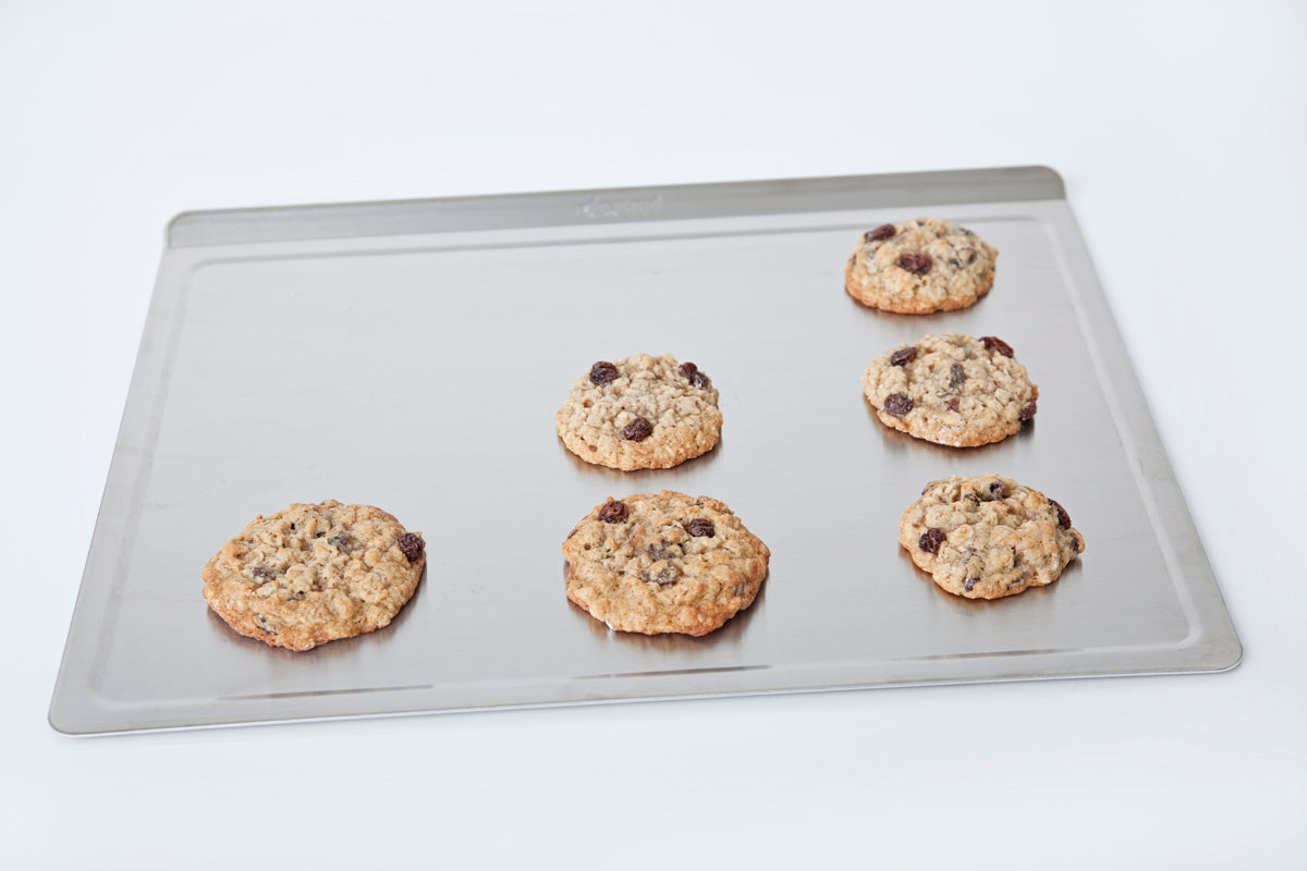 Six cookies on a baking tray with a white background