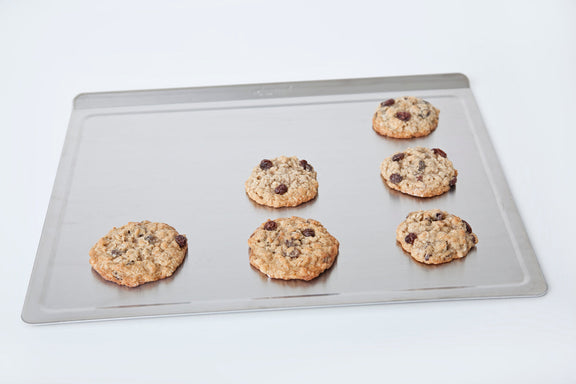 Six cookies on a baking tray with a white background