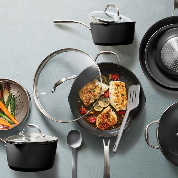 Collection of cookware including pots, pans, and utensils on a light blue background
