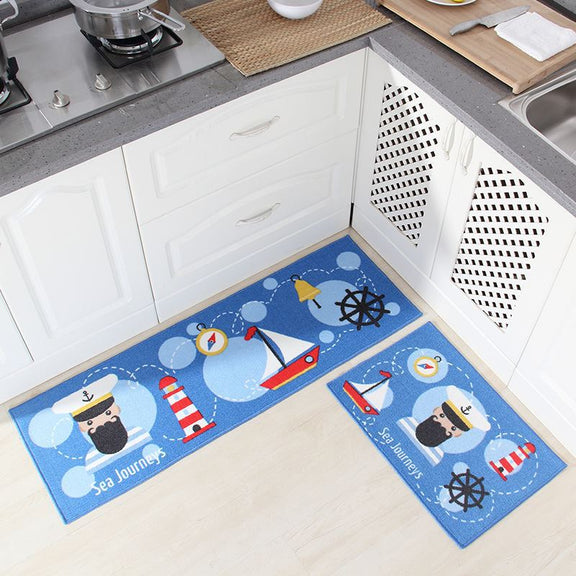 Kitchen floor with cartoon-themed mats featuring a captain, lighthouse, and sailboat design.