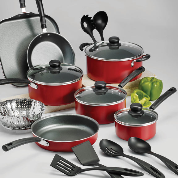 Picture of red cookware set with kitchen utensils and glass lids on grey background