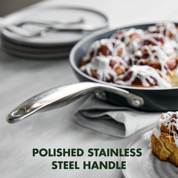 Stainless steel greenpan frying pan with a polished handle on a kitchen counter with cinnamon rolls.
