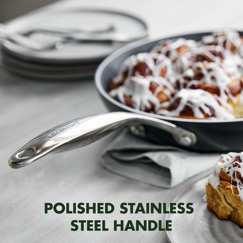 Stainless steel greenpan frying pan with a polished handle on a kitchen counter with cinnamon rolls.