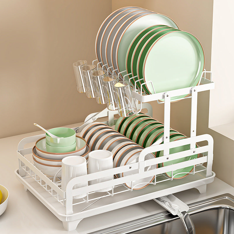 White dish rack with green and beige dishes on a kitchen counter.