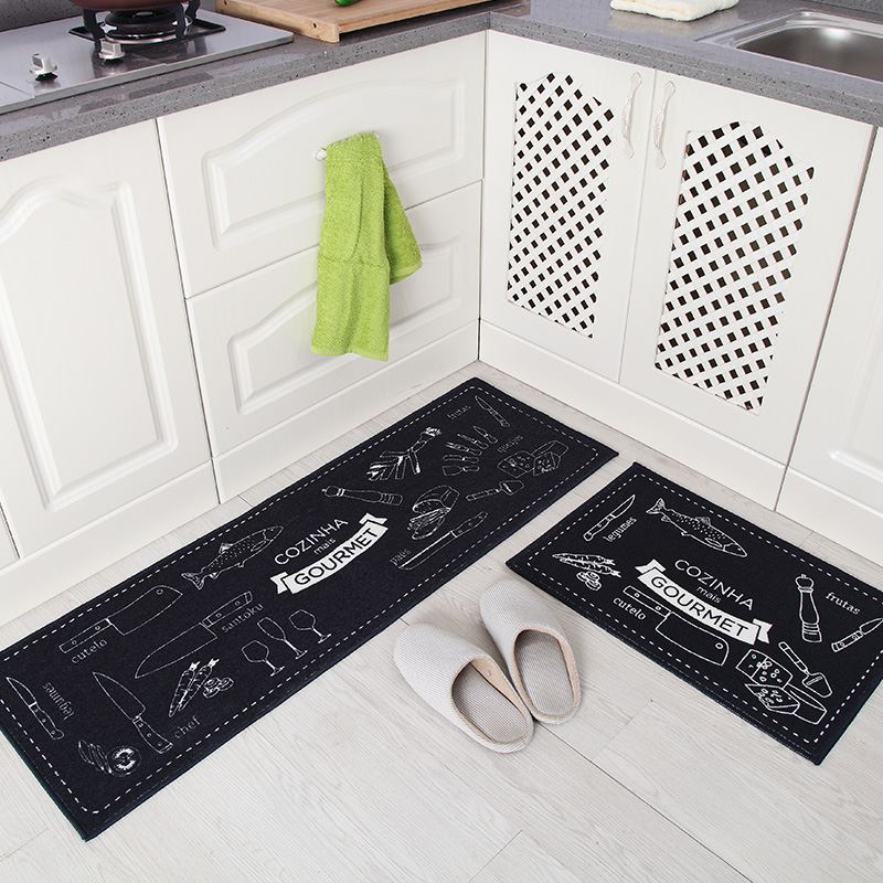 Black kitchen mats with white text and graphics on a kitchen floor.