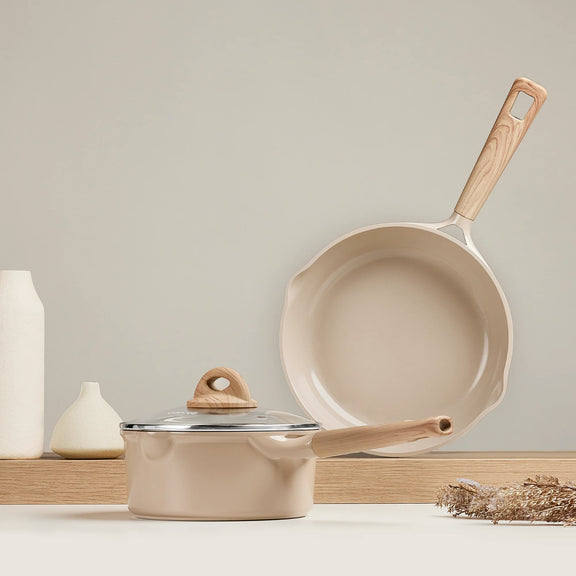 Beige cookware set with wooden handles on a neutral background