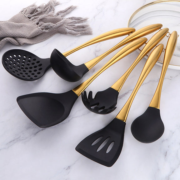 Set of black and gold kitchen utensils on a marble surface