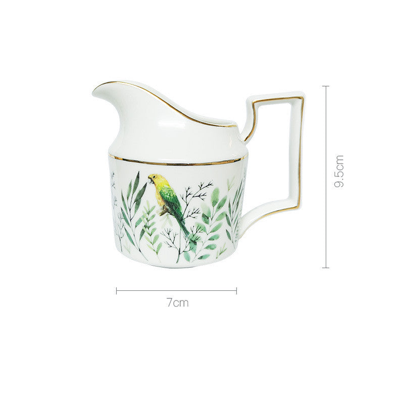 Ceramic creamer with bird and leaf design on a white background