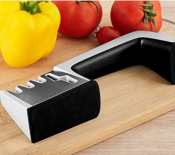 Knife sharpener on a wooden surface with vegetables in the background