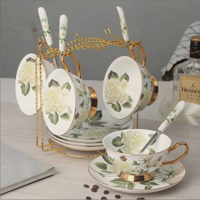 Ceramic tea set with floral design on a table with Hennessy VSOP cognac bottle in the background.