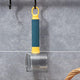 Blue and yellow tool hanging on a wall with a clear cylindrical object below.