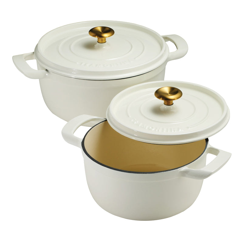 Two white enameled cast iron dutch oven cookware pots with gold interior and lids on a white background