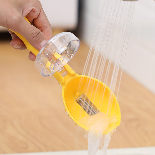 Yellow cat litter scoop with water being poured over it on a wooden surface.