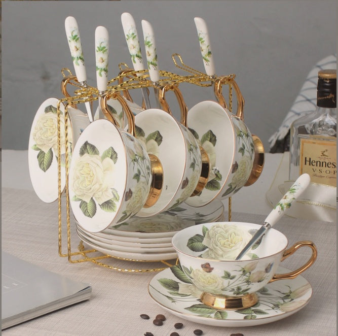 Set of ceramic tea cups and saucers with floral design on a decorative stand.