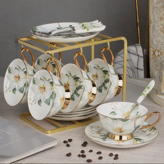 Tea set with floral design on a gold stand against a neutral background