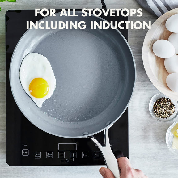 Gray Greenpan frying pan with an egg on a stovetop, surrounded by ingredients.